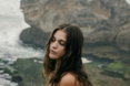 Woman in white clothes crouching on rocks by the ocean